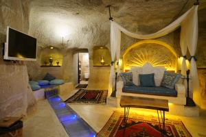a living room with a couch and a tv at Cappadocia Nar Cave House & Swimming Pool in Nevşehir
