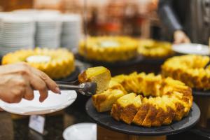 a person is holding a spatula cutting a piece of pie at Hotel Dan Inn Curitiba Centro By Nacional Inn in Curitiba