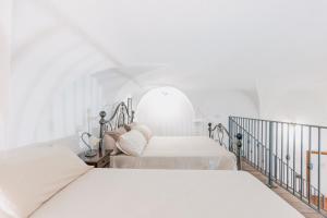 two beds in a white bedroom with an archway at BHR - Il Nido di Trevi in Trevi