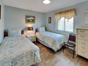 a bedroom with two beds and a chair and a dresser at Lighthouse Point 3B in Tybee Island +32 photos