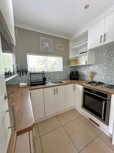 a kitchen with white cabinets and a sink at Wellway Place in Durbanville +6 photos