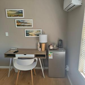 a desk with a white chair next to a refrigerator at Wellway Place in Durbanville