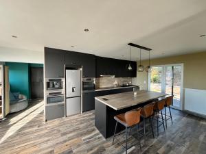 a kitchen with black cabinets and a table and chairs at Villa bel horizon avec jacuzzi in Hotton