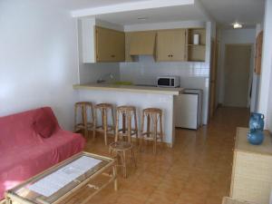 a living room with a red couch and a kitchen at Gran Sol C 01 in L'Escala