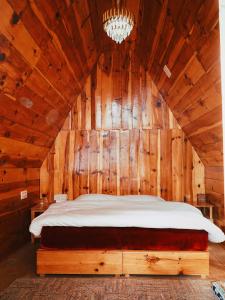 a bedroom with a bed in a wooden wall at Hima 360, A Frame Cabin, Panaromic Sainj Valley Views, Bhatkanda in Sainj