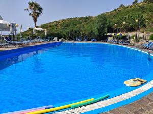 a large swimming pool with blue water and chairs at L'Oasi del Tramonto - Vista mare panoramica, Relax tra Agropoli e Cilento in Agropoli