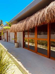 a building with a thatched roof and a patio at Pousada Oribá Chalé Boutique Milagres - AL in São Miguel dos Milagres