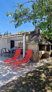two red chairs sitting in front of a stone fireplace at Cocooning et Charmante Maisonnette Provençale, avec Extérieurs privatifs et Accès Piscine in Orgon