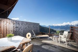 a wooden deck with tables and chairs and mountains at Alpenrelax Krepperhütte in Volders