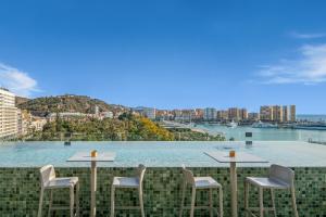 a row of tables and chairs on a balcony overlooking the water at Only YOU Hotel Málaga in Málaga