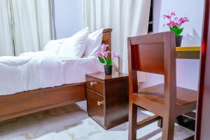 a bedroom with a bed and a chair and flowers at Cozycore Airnbn in Dodoma +22 photos