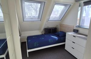 a small bedroom with a bed and two windows at Bungalowpark Simpelveld - Alpha 95 in Simpelveld