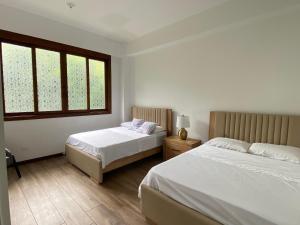 a bedroom with two beds and two windows at Casa Colonial Maria Elena in Pereira +32 photos
