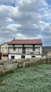 a white building with a red roof and a wall at Gaia Merindades in Salinas de Rosío