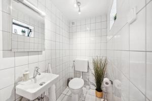 a white bathroom with a toilet and a sink at ANDRISS - Travel & Work - 5 BR - Kitchen - Parking in Kaiserslautern +16 photos
