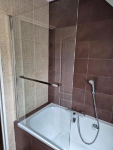 a bath tub with a glass shower in a bathroom at Floralie parking privé navette vers Aéroport ou Gare Beauvais in Saint-Paul +19 photos
