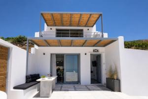 a white house with a wooden roof at Tinian Sunset Villa in Istérnia