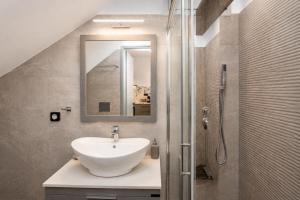 a bathroom with a sink and a shower with a mirror at Tinian Sunset Villa in Istérnia