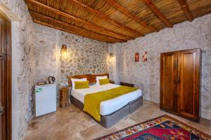a bedroom with a bed in a stone walled room at Cappadocia Nar Cave House & Swimming Pool in Nevşehir +158 photos