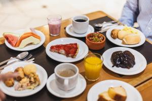 a table with plates of breakfast food on it at Hotel Dan Inn Curitiba Centro By Nacional Inn in Curitiba