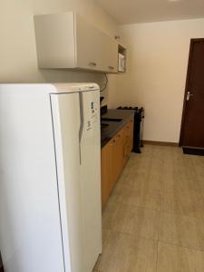 a kitchen with a white refrigerator in a room at Casa da Dinda 105 in Rio das Ostras