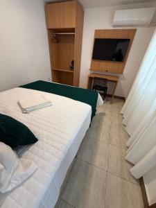 a hotel room with two beds and a television at Casa da Dinda 105 in Rio das Ostras