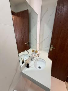 a bathroom with a sink and a mirror at Casa da Dinda 105 in Rio das Ostras