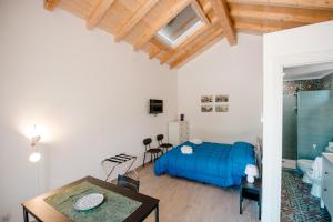 a bedroom with a blue bed and a dining table at Malicodia in Santa Maria di Licodia