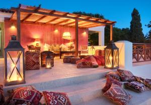 a patio with pillows and a pergola with lights at Purple Apricot Hotel in Vlachopoulátika