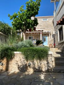 a house with a tree and a stone wall at Kranidi House. in Kranidi