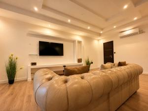 a living room with a large couch and a tv at Spacious Townhouse - Private Jacuzzi -Swieqi in Is-Swieqi
