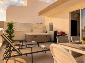 a patio with a table and chairs on a balcony at Spacious Townhouse - Private Jacuzzi -Swieqi in Is-Swieqi