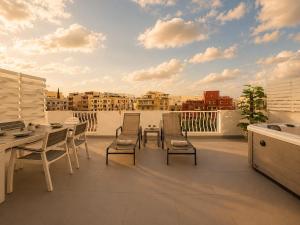 a patio with a table and chairs on a balcony at Spacious Townhouse - Private Jacuzzi -Swieqi in Is-Swieqi
