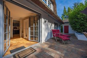 a patio with two chairs and a sliding door at Weiße Reetdachkate Wohnung 1 in Stöfs
