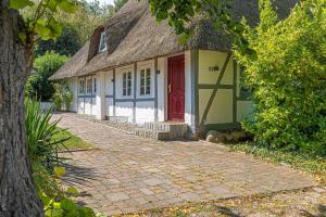 a small house with a thatched roof and a brick driveway at Weiße Reetdachkate Wohnung 1 in Stöfs +42 photos