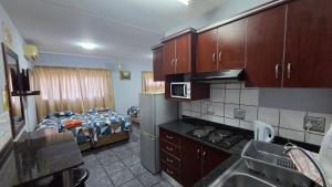 a room with a kitchen and a bedroom with a bed at Beginners Cove Lodge in Nelspruit