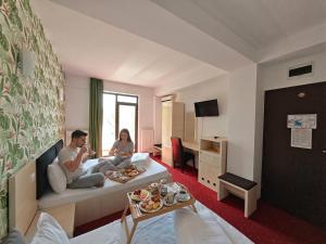 a man and woman sitting on a couch in a hotel room at Alma by iVAVev Is'us in Mamaia