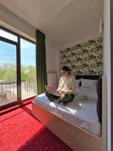 a woman sitting on a bed with a laptop at Alma by iVAVev Is'us in Mamaia +217 photos