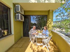 a man and woman sitting at a table on a porch at Alma by iVAVev Is'us in Mamaia