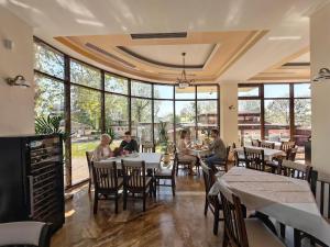 a group of people sitting at tables in a restaurant at Alma by iVAVev Is'us in Mamaia