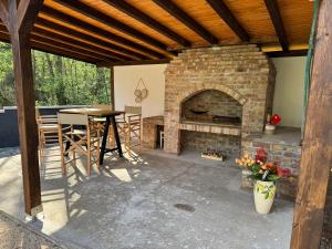 a patio with a brick fireplace and a table at Maca - vikendica sa bazenom in Ahatovići