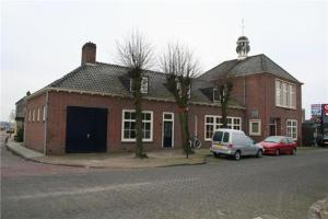 a red brick building with cars parked in front of it at De Kazerne - Beulaker wijde in Wanneperveen