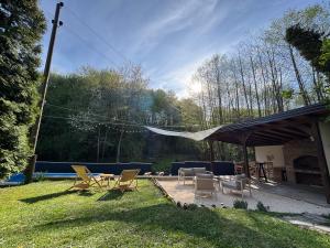 a patio with chairs and a table and a tent at Maca - vikendica sa bazenom in Ahatovići