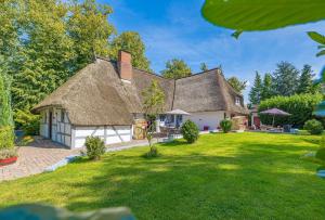 a house with a thatched roof and a yard at Weiße Reetdachkate Wohnung 2 in Stöfs +42 photos