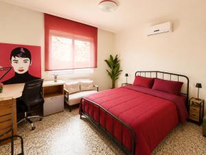 a bedroom with a red bed and a desk and a computer at Casa Verna Jacuzzi y Barbacoa in Murcia