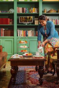 a woman standing in a room with a coffee table at The Majestic Malacca, Melaka - Small Luxury Hotels of the World in Malacca