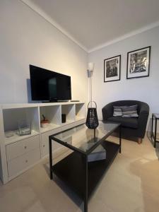 a living room with a tv and a glass table at Sunset Paradise in Caminha