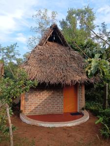 a small brick building with a grass roof at Rootscape Huts Hostel and Home Stay in Auroville