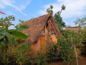 an orange house with a thatched roof at Rootscape Huts Hostel and Home Stay in Auroville