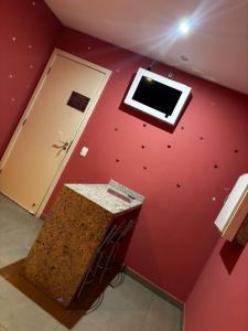 a room with a red wall with a window at Classik Prime Motel in Araçatuba